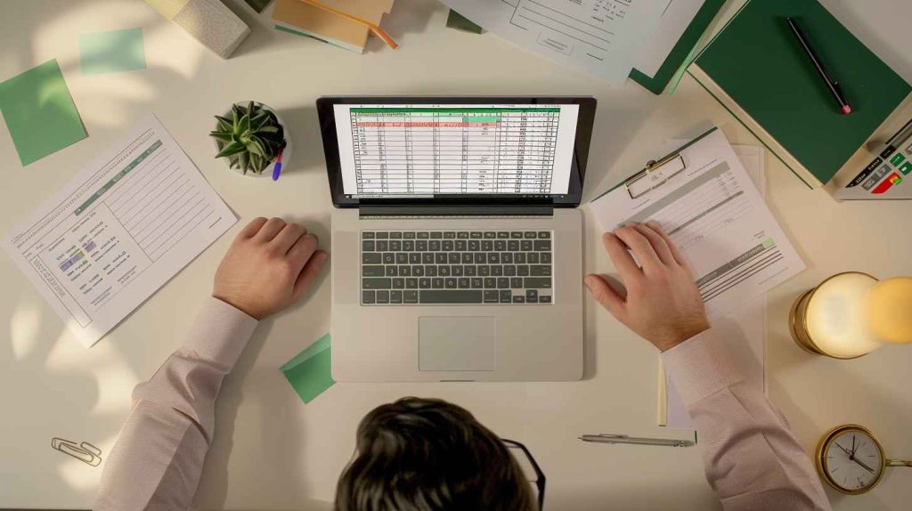 A male professional using Excel in a well-organized workspace for a data entry task.